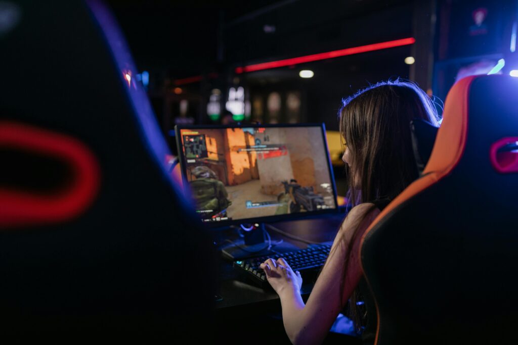 A woman is deeply engaged in playing computer games indoors, highlighting the gaming lifestyle.